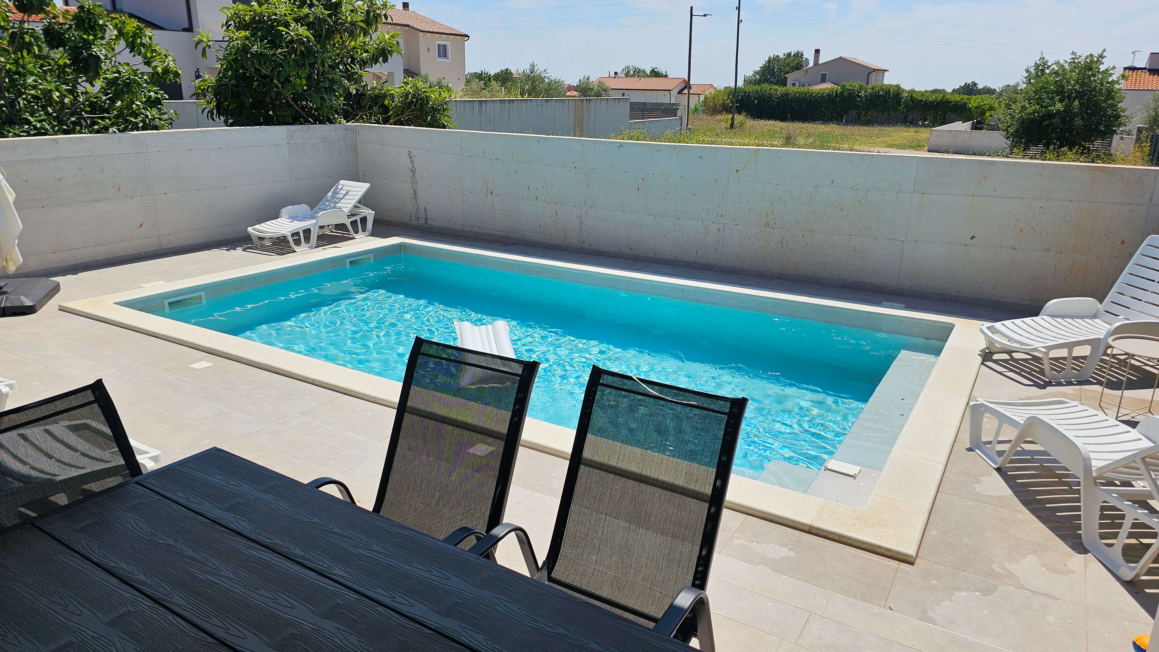 Pogled na bazen i ležaljke s vanjske terase u Vili Mia