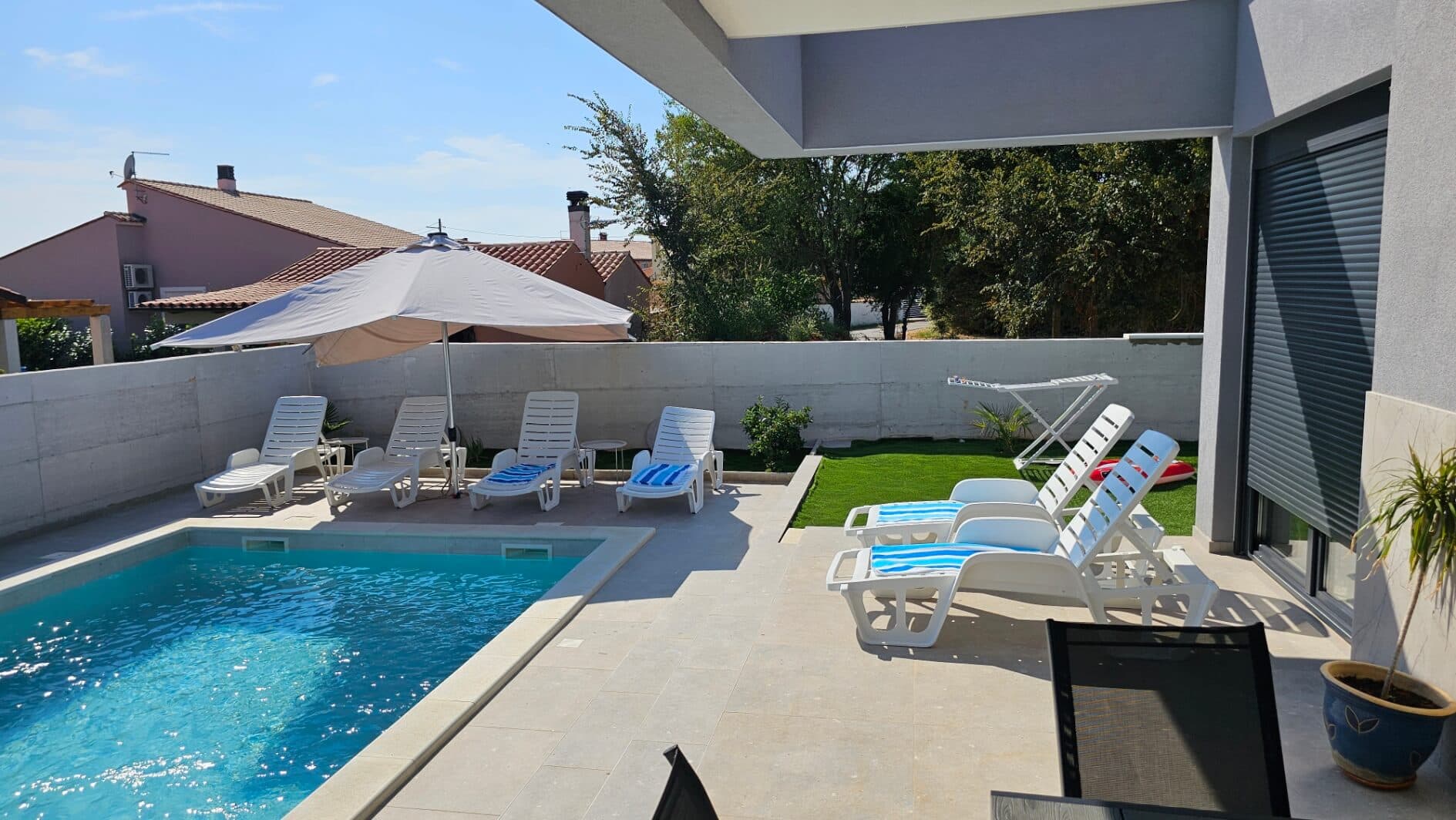 Vanjski bazen s velikim suncobranom u Vili Teo